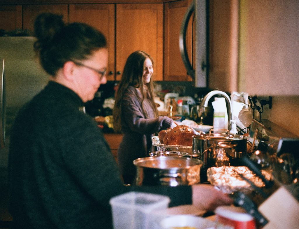 Two people cooking in a messy kitchen